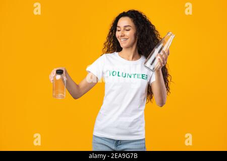 Volontario femminile che sceglie tra bottiglia di vetro e plastica in Studio Foto Stock