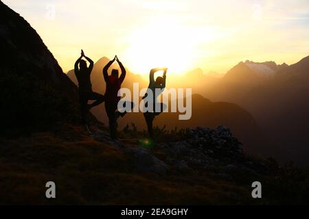 3 giovani donne al tramonto in direzione dei Monti Wetterstein, registrate sul Gamseck sopra il rifugio Mittenwalder Foto Stock