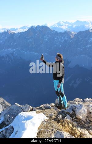 Escursione al Pleisenspitze (2569 m), giovane donna fa selfie sulla cima, Karwendel montagne sullo sfondo, tour in montagna, escursioni in montagna, all'aperto Foto Stock