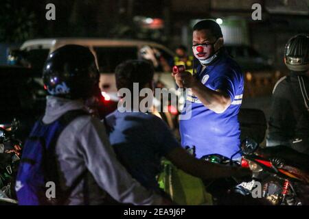 Un poliziotto controlla la temperatura corporea e l’identificazione delle persone in un checkpoint dopo essere stato dispiegato come parte della misura preventiva del governo contro la diffusione del coronavirus nel Metropolita Manila, Filippine. Foto Stock