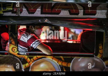 I passeggeri a bordo di una jeepney indossano maschere facciali di protezione vicino a un checkpoint implementato come parte della misura preventiva del governo sulla diffusione del coronavirus nella periferia di Manila, Filippine. Foto Stock