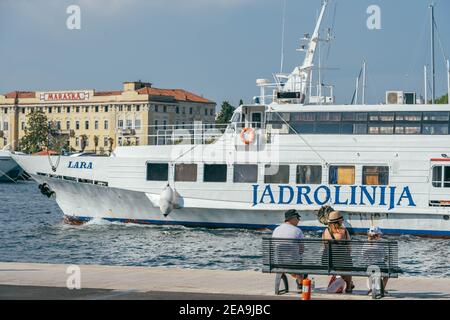 Zadar, Croazia - 13 agosto 2020: Riposo familiare in panchina presso il porto della città vecchia nel pomeriggio Foto Stock