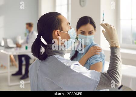 Medico che tiene una siringa con un farmaco che rilascia un flusso di farmaco per eliminare le bolle d'aria. Foto Stock