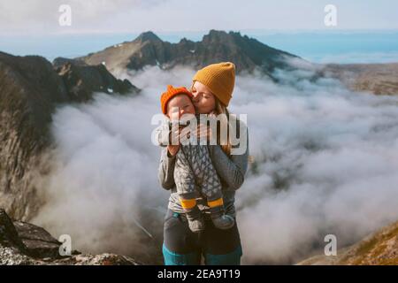 Madre baciare bambino famiglia bambino escursioni in montagna vacanze attive viaggi donna all'aperto con bambino sopra le nuvole sano viaggio di stile di vita In Norvegia Foto Stock