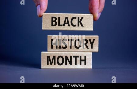 Simbolo del mese della storia nera. Blocchi di legno con parole 'mese della storia nera'. Splendido sfondo grigio. Mano dell'uomo. Storia nera concetto mese. Copia spa Foto Stock