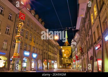 Berna, Svizzera - 23 agosto 2020: Scena urbana notturna di Marksman Fountain o Schutzenbrunnen sulla via del mercato di Marktgasse e la Torre dell'Orologio di Zytglogge Foto Stock