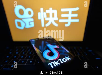 In questa illustrazione fotografica il logo TikTok visualizzato su un telefono cellulare davanti al logo Kuaishou sullo schermo di un computer. Foto Stock