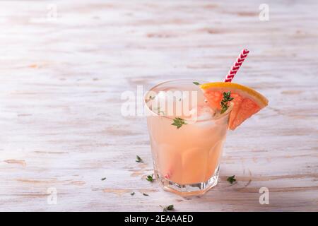 Limonata di pompelmo con timo in un bicchiere su fondo di legno, spazio libero, fuoco selettivo. Bevanda rinfrescante sana Foto Stock