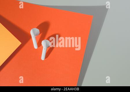 le cuffie wireless bianche si trovano su uno sfondo colorato, da un eccellente dispositivo analogico a un dispositivo audio più costoso. Foto Stock