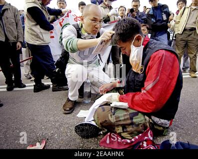 Gli agricoltori sudcoreani ricevono assistenza medica dopo uno scontro con la polizia di Hong Kong al di fuori del Centro Convegni di Hong Kong, dove i delegati si riunono alla sesta Conferenza ministeriale dell'Organizzazione Mondiale del Commercio il 17 dicembre 2005. I coreani del sud hanno b Foto Stock