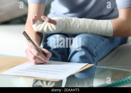 Primo piano ritratto di una donna disabile con braccio bendato documento di assicurazione sigining Foto Stock