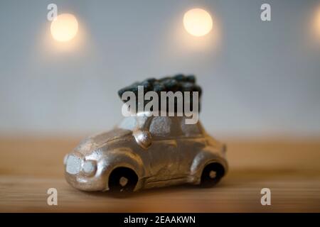 Still life, piccola auto d'oro con un abete sul tetto di fronte ad una catena di luci, romantico umore natalizio Foto Stock
