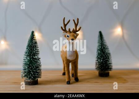 Decorazione di Natale, piccolo cervo peluche tra due alberi di Natale luci fata, umore di Natale, Foto Stock