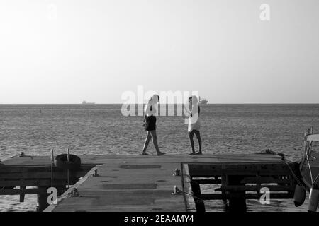 due giovani donne in piedi alla fine del jetty grand anse spiaggia grenada isole ventoso indie occidentali Foto Stock