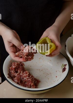 le mani della donna riempiono i peperoni con carne tritata Foto Stock