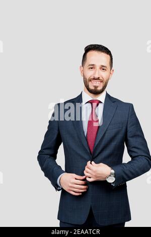 Bell'uomo d'affari arabo in tuta sorride su sfondo bianco in studio. Ritratto di affari dell'uomo riuscito Foto Stock