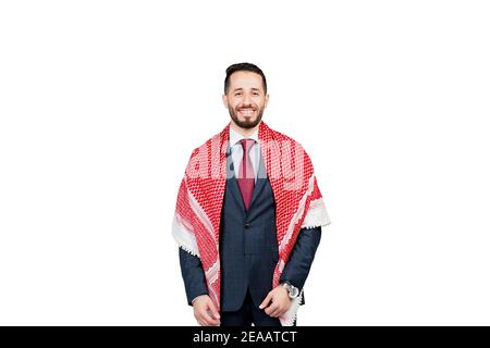 Bell'uomo d'affari arabo in tuta e shemagh sorride su sfondo bianco in studio. Ritratto di affari dell'uomo riuscito Foto Stock
