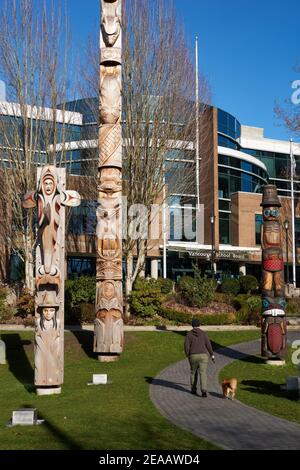 Kwakiutl stile riconciliazione totem pole e Coast Salish Welcome Posts al di fuori del Vancouver School Board edificio, Vancouver, BC, Canada Foto Stock