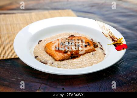 Risotto con filetto di salmone alla griglia e salsa alla frutta Foto Stock