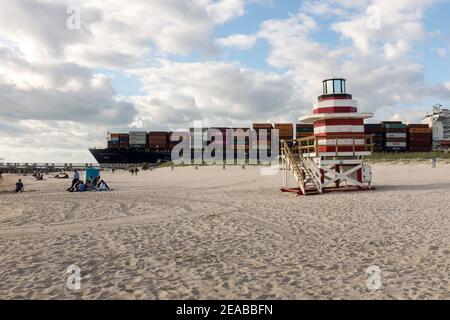 Una nave container completamente caricata salpa da una torre di bagnino al largo di South Beach, Miami Beach, Florida Foto Stock