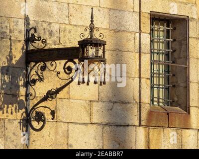Vecchia lampada e finestra in ferro battuto con barre di sicurezza sulla parete stellare del Convento di San Paio de Antealtares - Santiago de Compostela, Spagna Foto Stock