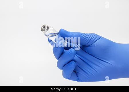 La mano del medico con il guanto medico usa e getta tiene il flacone di vaccino in mano, il dettaglio, la foto di simbolo, il coronavirus, la vaccinazione, Foto Stock