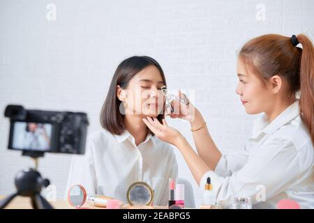 Due giovani donne asiatiche bellezza vlogger video on-line è mostrare trucco su prodotti cosmetici e video dal vivo su fotocamera digitale. Foto Stock