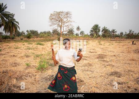 una donna africana che tiene il suo telefono e mostra l'espressione di sorprese Foto Stock