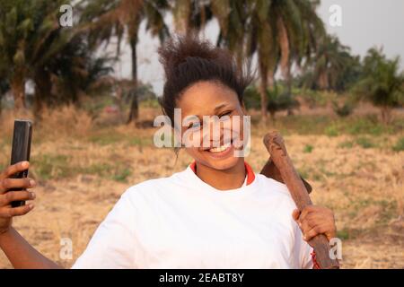 una donna africana che porta una zappa Foto Stock