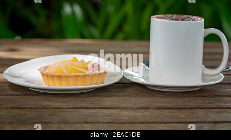 Cappuccino con crostata di limone e agrumi all'aperto tavola di legno Foto Stock