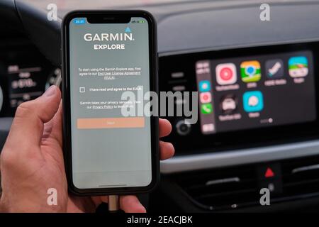 Logo Garmin Explore sullo schermo dello smartphone in mano di mans sullo sfondo della schermata del cruscotto dell'auto con applicazione di navigazione o mappe Foto Stock