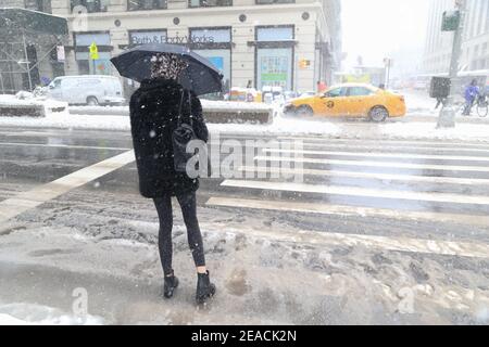 New York City, NY USA Woman camminando attraverso la neve e la neve sulla 23esima strada. Foto Stock