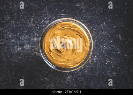 Burro di arachidi nel recipiente sul tavolo nero. Vista dall'alto. Foto Stock