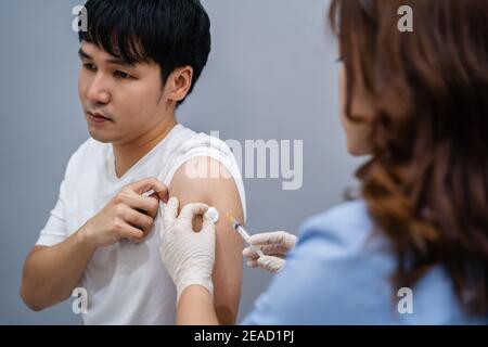 medico che tiene la siringa e che usa un cotone prima di fare l'iniezione al paziente. Vaccino Covid-19 o coronavirus Foto Stock