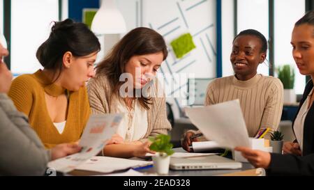 Diversi team di colleghi professionisti, brainstorming in un incontro d'affari sotto l'occhio vigile della boss donna africana. Black director Company che valuta i dipendenti seduti alla scrivania in discussione Foto Stock