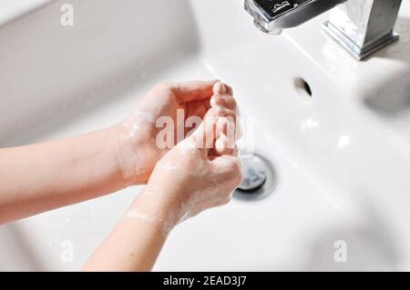 Concetto di bianco europeo bambino (ragazza, capretto) che pulisce le mani con sapone schiumoso sopra il lavandino (lavabo). Foto Stock