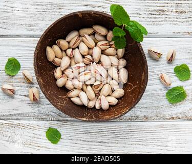 Ciotola con pistacchi su un tavolo di legno Foto Stock