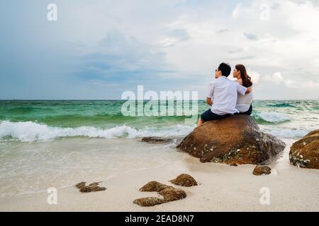 Giovane coppia che si aggirano sulla roccia della spiaggia di mare a Koh MunNork Island, Rayong, Thailandia Foto Stock