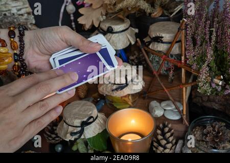 La mano della donna sta tenendo il mazzo delle carte del tarocco o dell'oracolo che fa la fortuna. Foto Stock