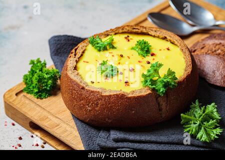 Zuppa di formaggio in una ciotola di pane su una tavola di legno. Concetto di cucina ceca. Foto Stock