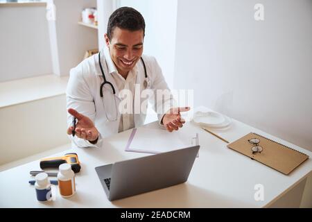 Medico professionista in bianco accappatoio guardando allo schermo di moderno computer portatile del centro medico Foto Stock