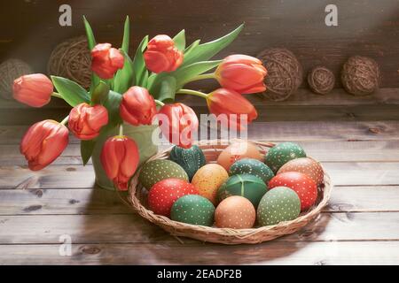 Mazzo di tulipani rossi, uova di Pasqua in vassoio di sonaglino decorazioni Springtime su rustico sfondo di legno. Immagine con tonalità retrò di Pasqua decorations.in bassa Foto Stock