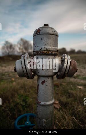 Vecchio idrante di fuoco su un campo di erba riempito con ruggine Foto Stock