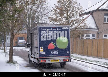 Merton, Londra, Regno Unito. 9 febbraio 2021. La nevicata mattutina più pesante nel sud di Londra si trova su strade suburbane non trattate, ma le strade principali in erba rimangono sgombrate senza scappatoie per il traffico. Un furgone Tesco per la consegna a casa al lavoro nella neve. Credit: Malcolm Park/Alamy Live News. Foto Stock