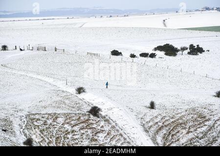 Brighton UK 9 febbraio 2021 - UN camminatore nella neve a Devils Dyke sulla strada di South Downs appena a nord di Brighton oggi come alcune parti della Gran Bretagna sperimentare il giorno più freddo dell'inverno finora: Credit Simon Dack / Alamy Live News Foto Stock