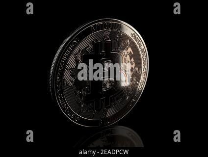 Una criptovaluta Bitcoin fisica scarsamente illuminata in bronzo e argento Forma a moneta su sfondo scuro dello studio - rendering 3D Foto Stock