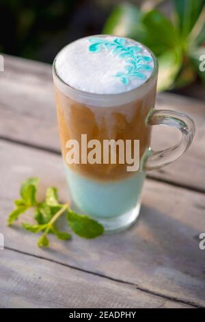 Menta con caffè ghiacciato in vetro con foglie di menta su sfondo di tavola di legno. Foto Stock