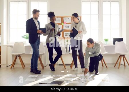 Gruppo di giovani uomini d'affari diversi che sviluppano strategia di affari in ufficio moderno Foto Stock