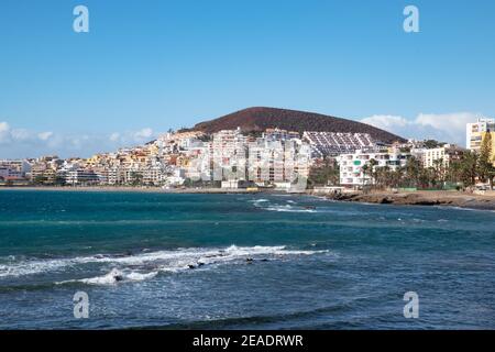 Ampia vista dal lato più orientale della piccola e popolare cittadina turistica verso gli hotel, gli edifici, la spiaggia e la costa, Los Cristianos, Tenerife Foto Stock