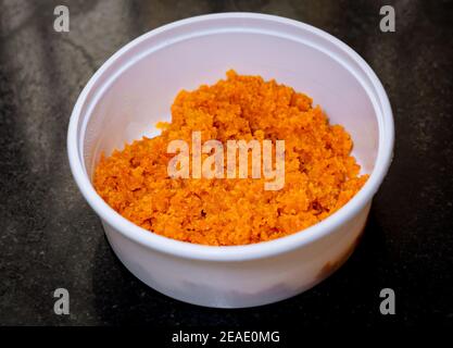 Primo piano di Carrot Halwa in una scatola da asporto bianca su uno sfondo di granito nero. Foto Stock